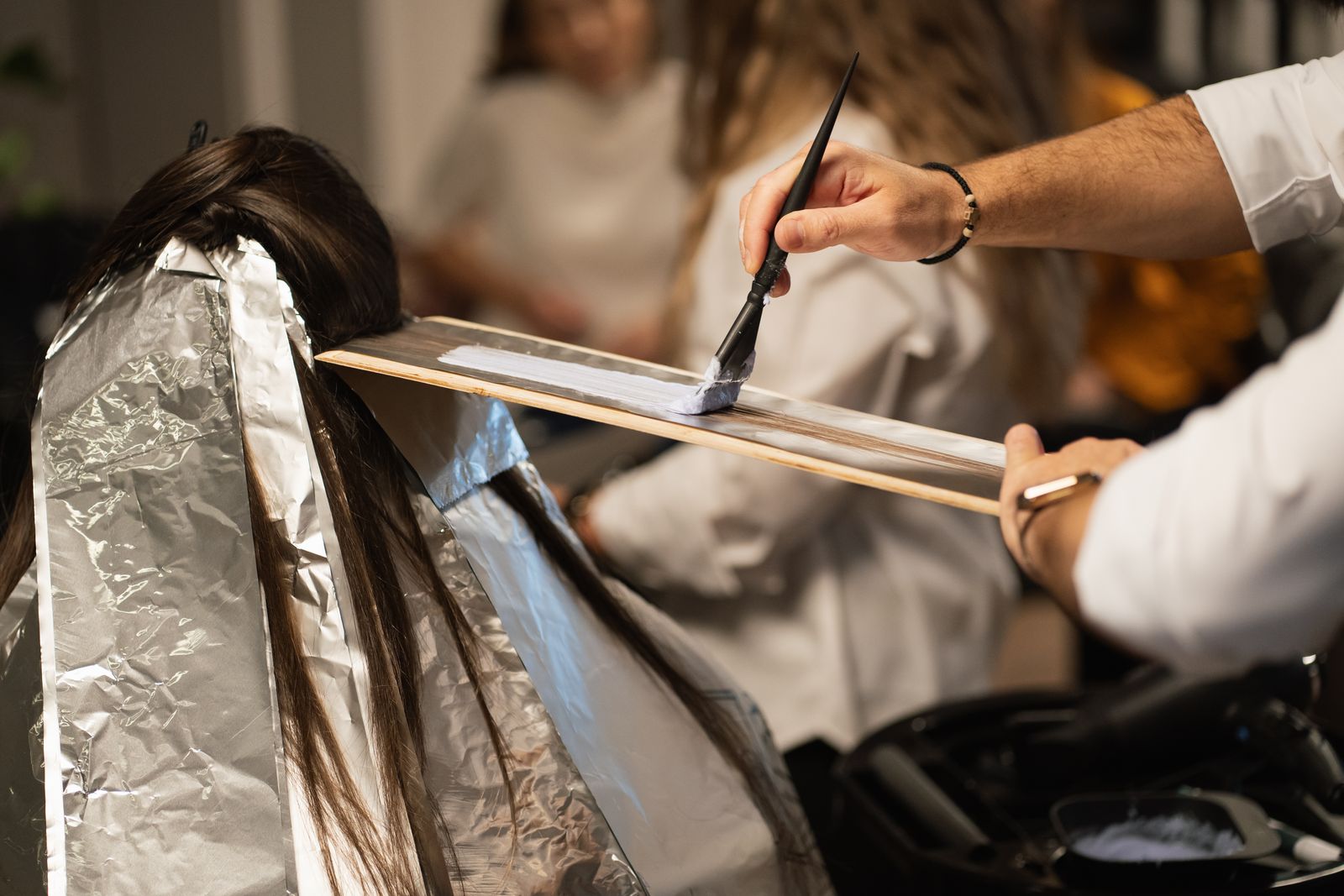 A colorist's hands painting foils during a color service