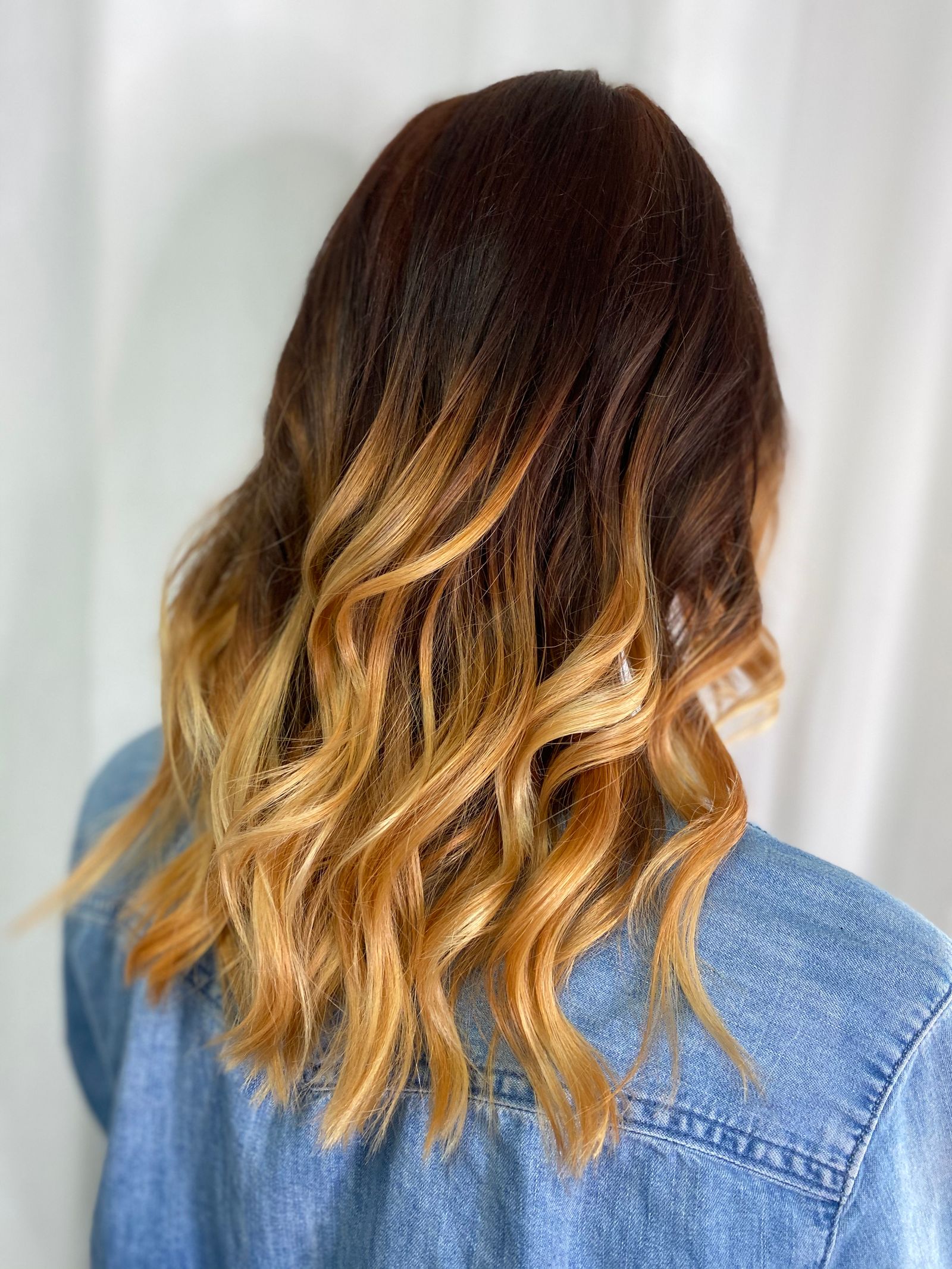 Back of a client's head showing natural caramel balayage waves